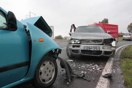 Dos turismos con la parte delantera destrozada tras una colisión frontal en una carretera.